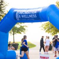 A participant finishing the event under a blue inflatable arch